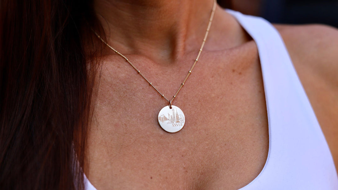 woman wearing a necklace engraved with the NYC skyline