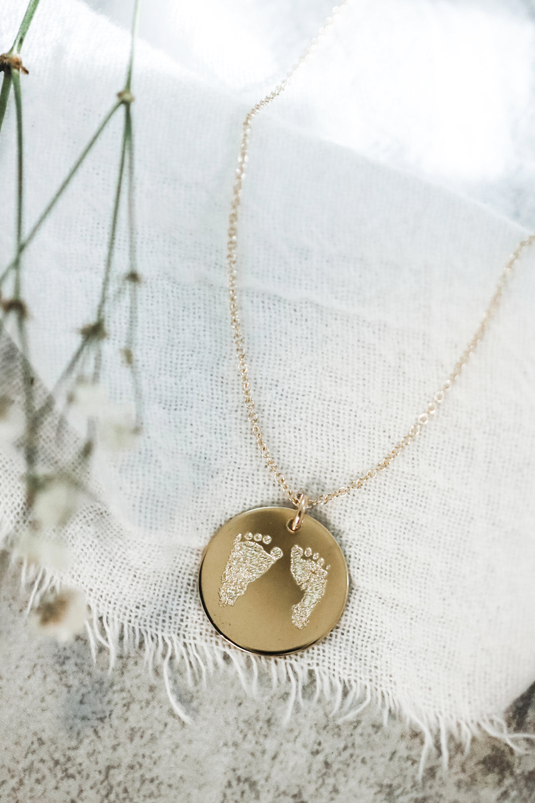 gold necklace engraved with baby footprints