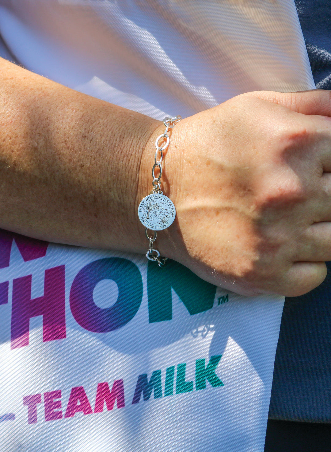 woman’s wrist wearing a silver Every Woman’s Marathon bracelet by Erica Sara