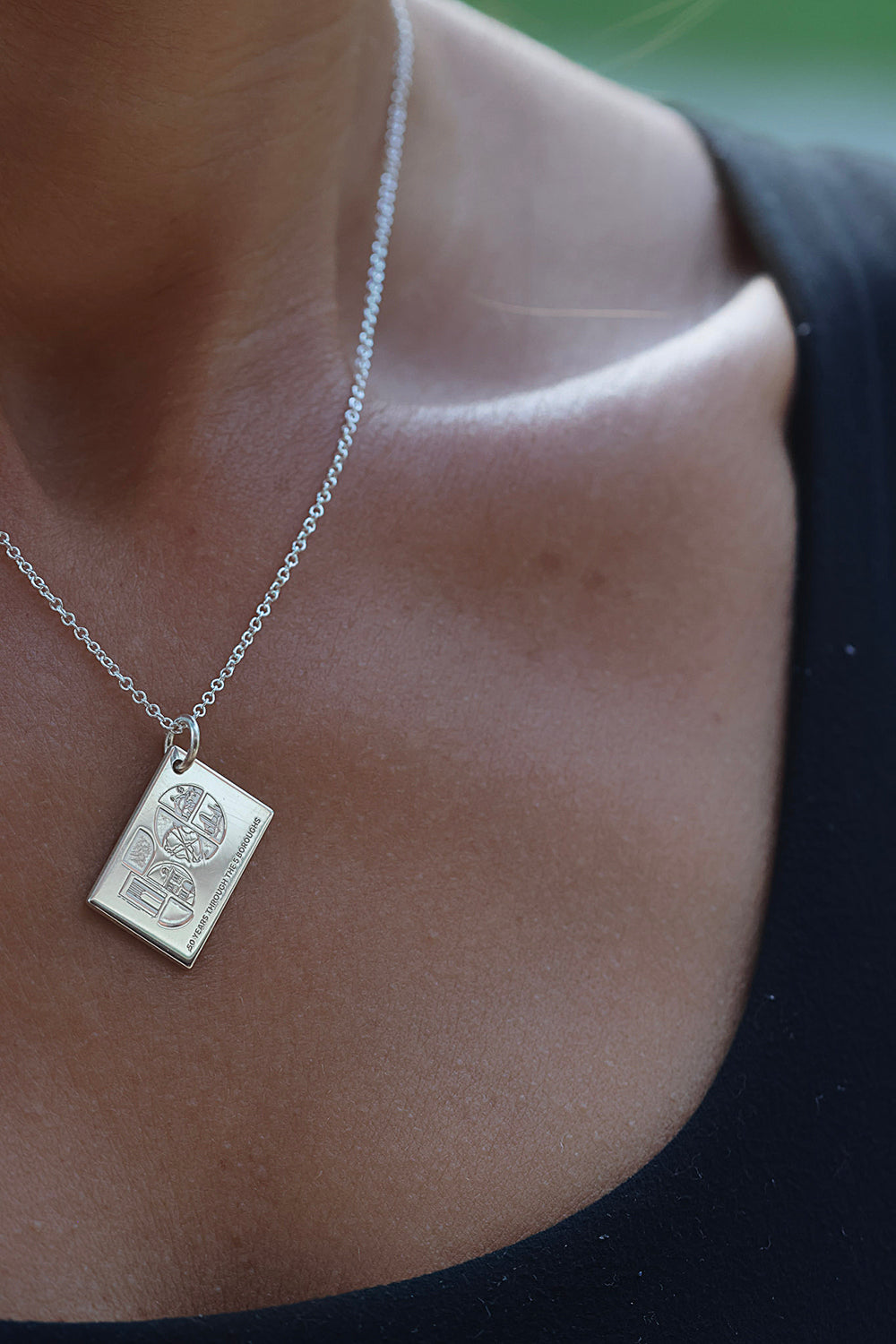 Woman wearing the TCS New York City Marathon five boroughs postcard necklace

